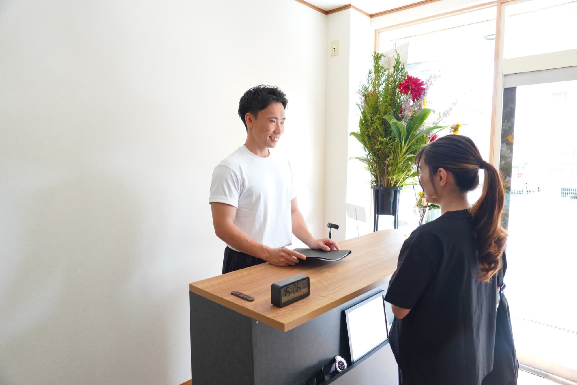受付でお客様を笑顔で迎えるトレーナー