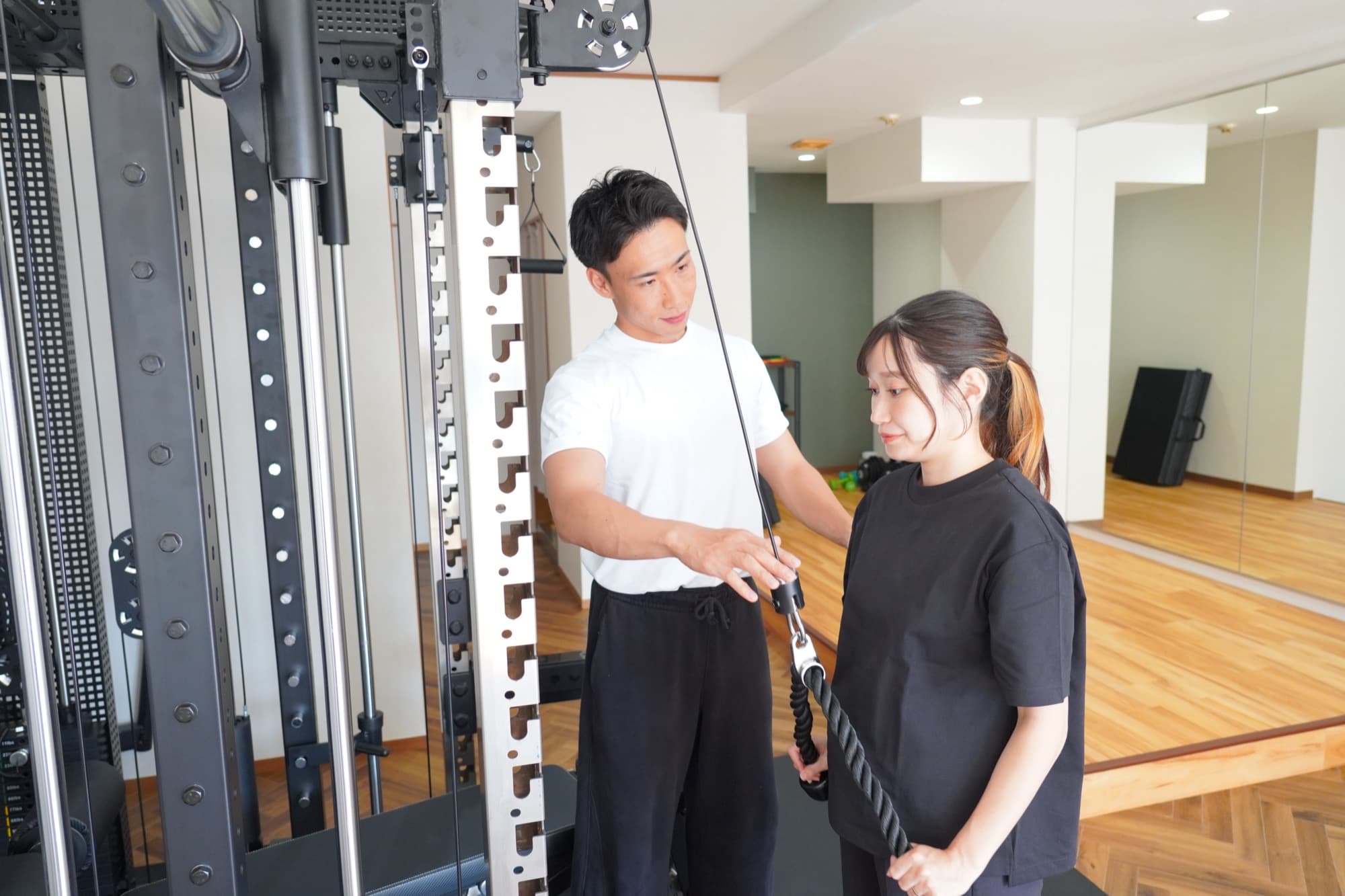 ケーブルマシンで指導するトレーナー